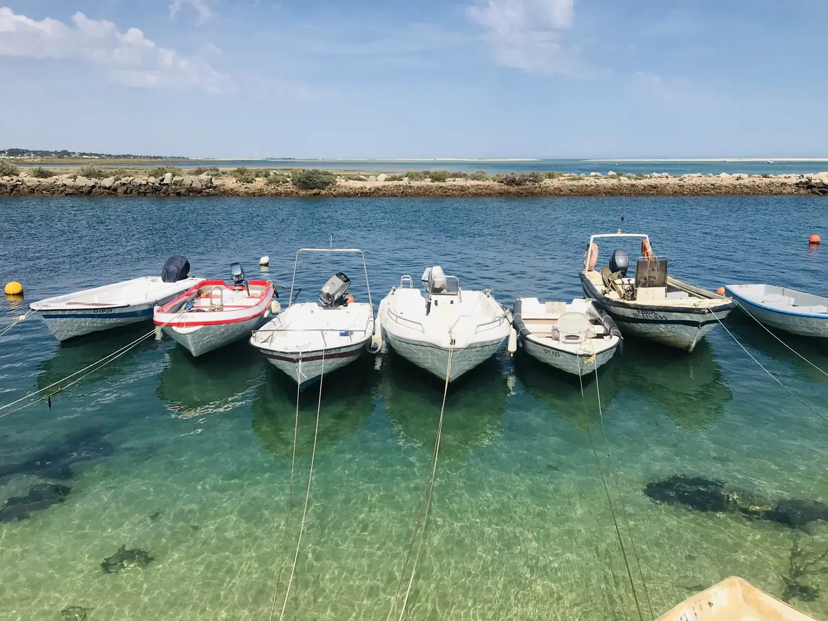 Barcos ancorados em água transparente na Fuseta